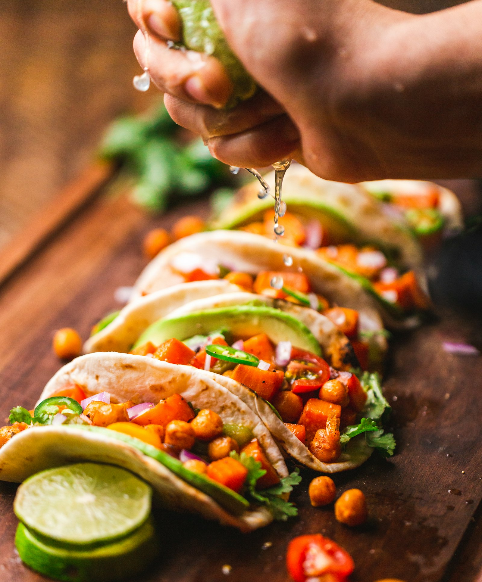 Fresh lime squeezed over a row of veggie tacos